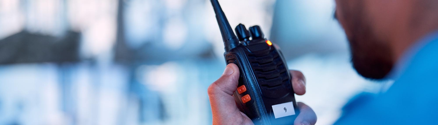 Back view of a male security personnel speaking through a walkie talkie