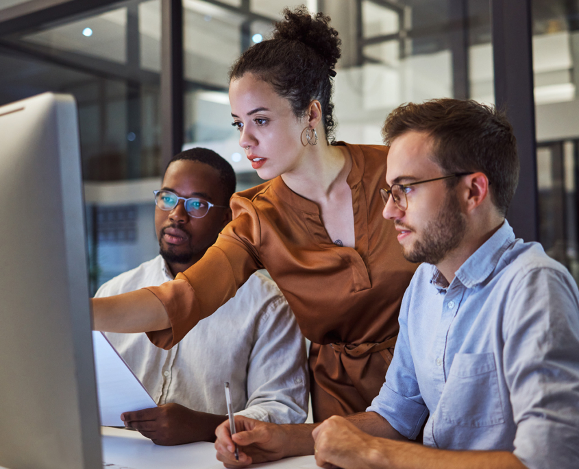 Side view of an IT professional helping her coworkers on computer