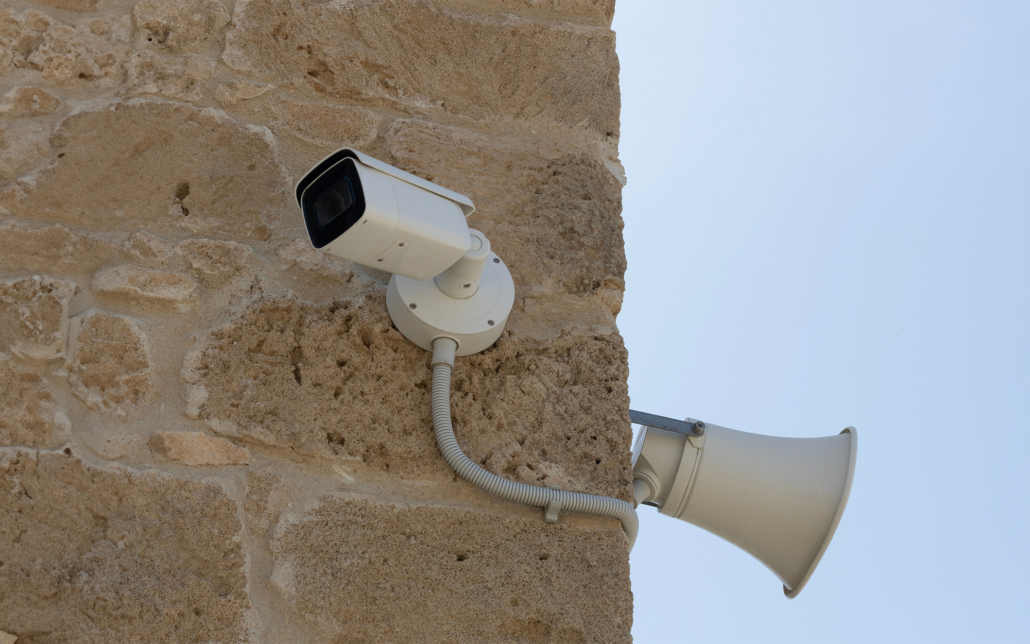 Side view of security camera and loudspeaker mounted on wall