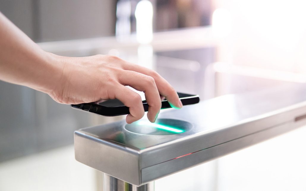 Male hand using smartphone to open automatic gate machine in office building