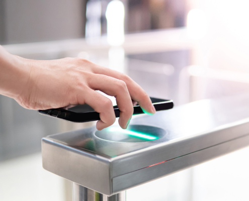 Male hand using smartphone to open automatic gate machine in office building
