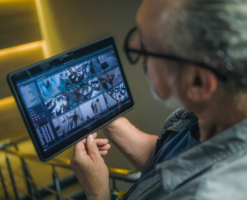 Male installer watches CCTV cameras in stylish office using tablet computer