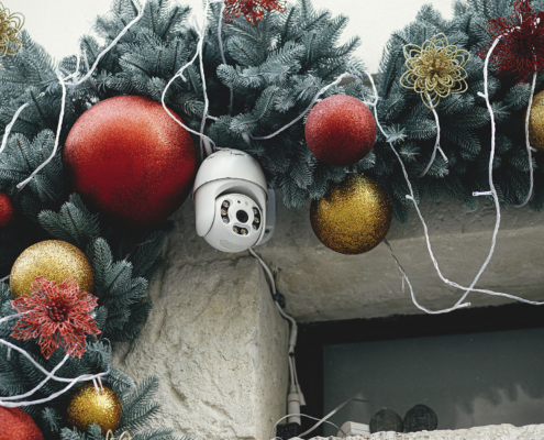 Stylish safety camera and christmas baubles on fir branches on building exterior